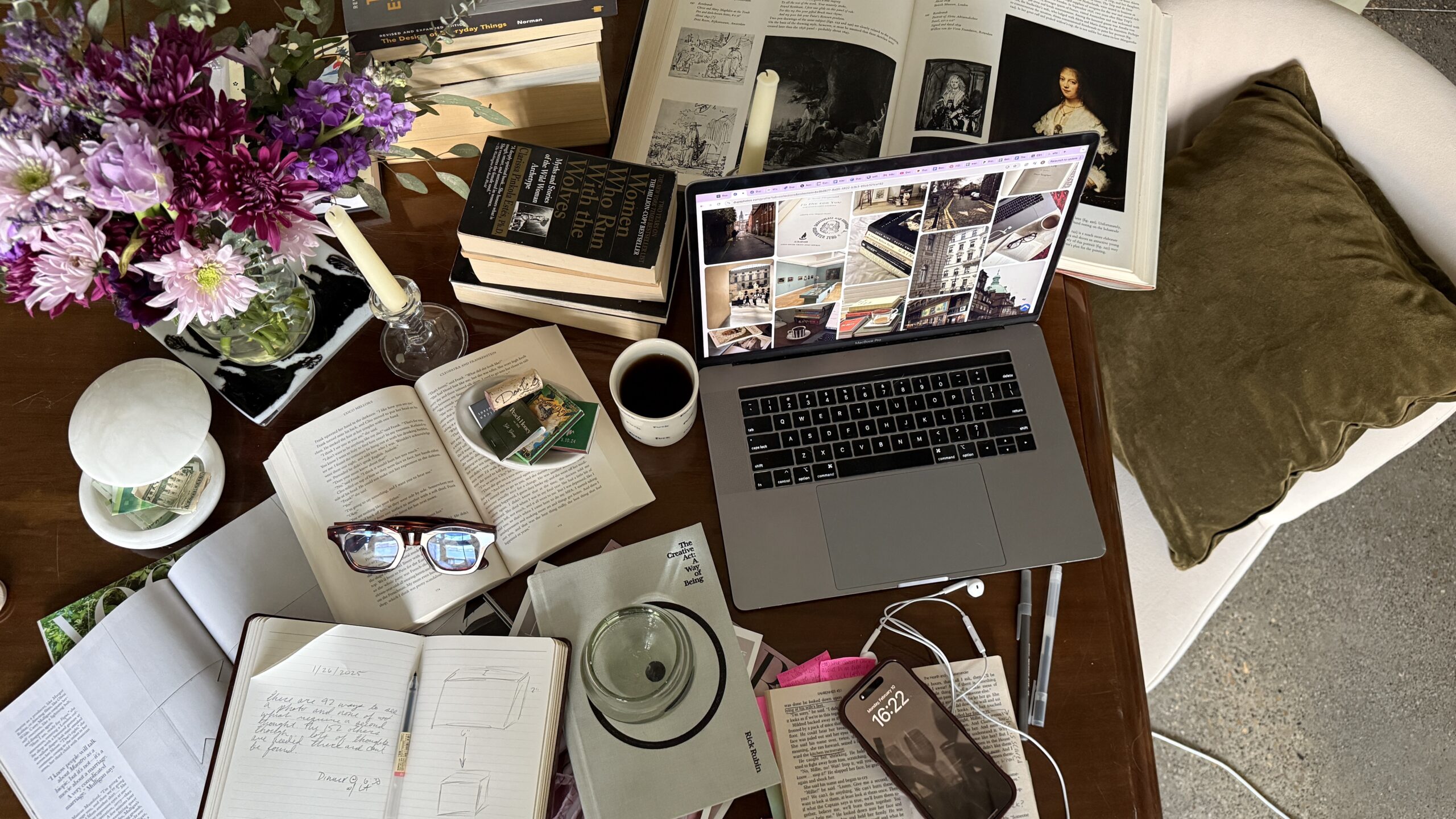 Editorial desk flat lay with laptop, books, notebook, coffee, flowers, and creative work-in-progress